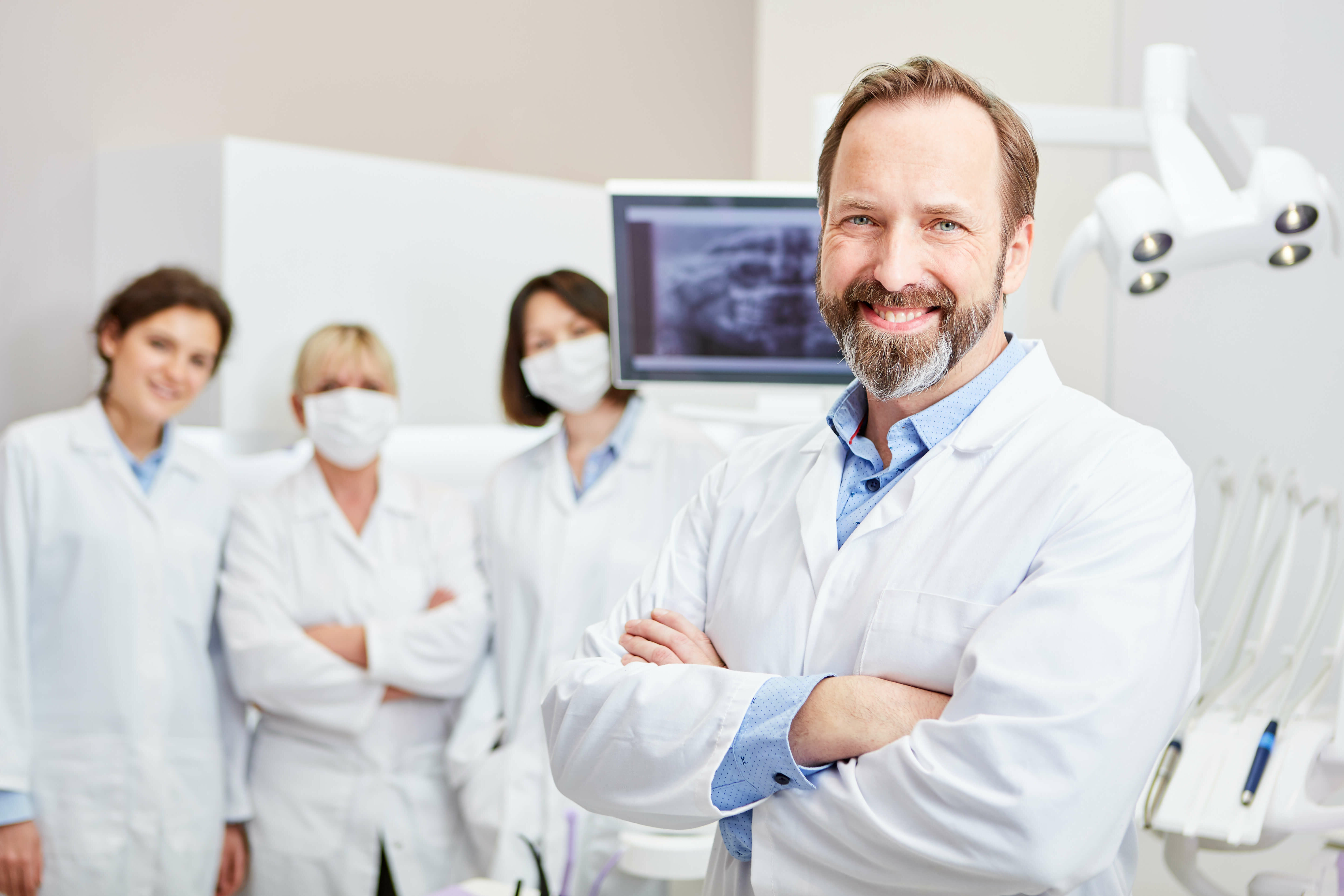 Zahnarzt mit Angestellten im Hintergrund