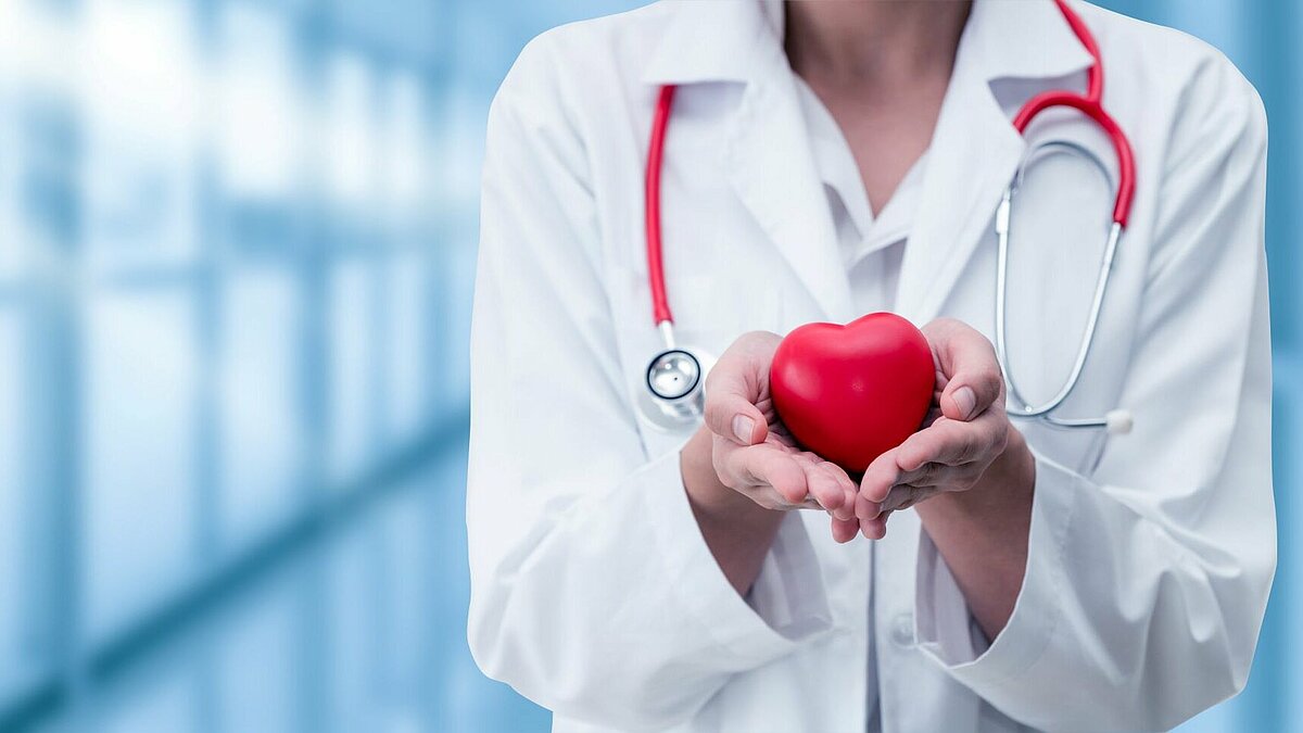 Ärztin hält ein Herz schützend in uhren Händen.
