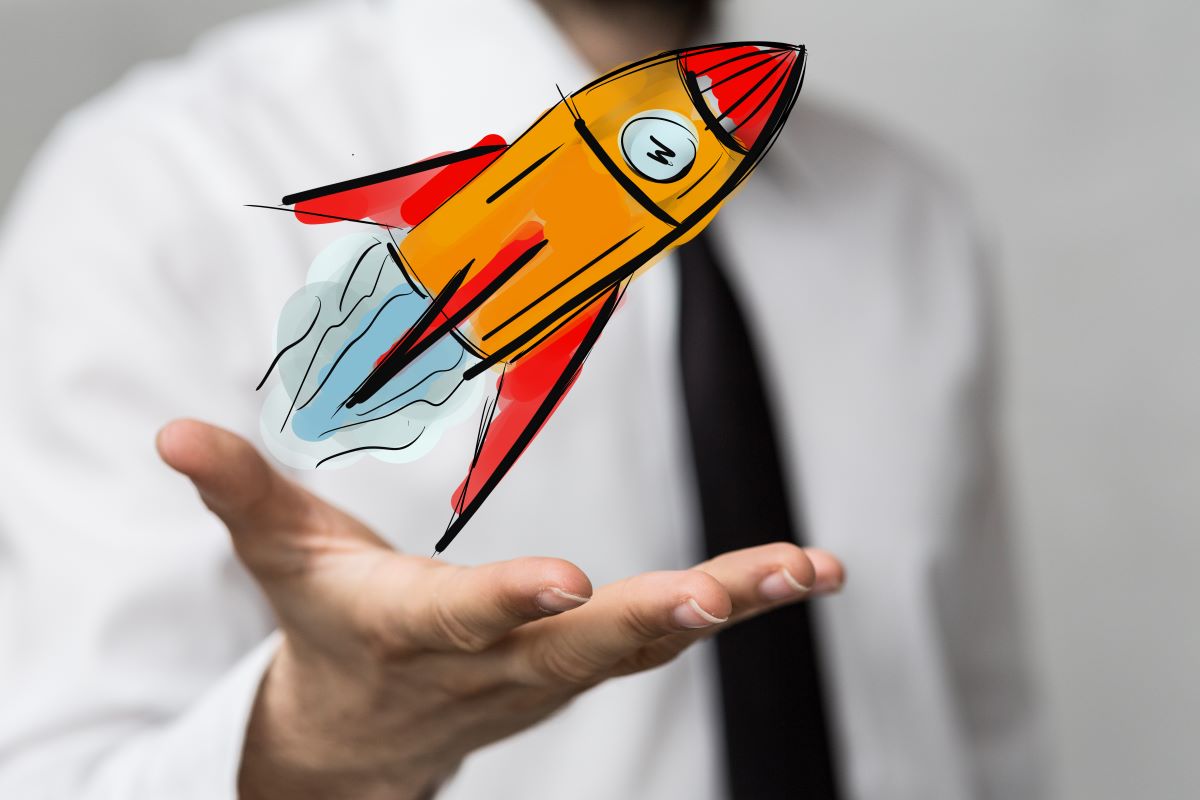 Ein Mann im weißen Hemd lässt aus seiner Hand symbolisch eine Rakete steigen. Das Bild ist eine Fotomontage und die Rakete ist im typischen Emoji-Stil gehalten.