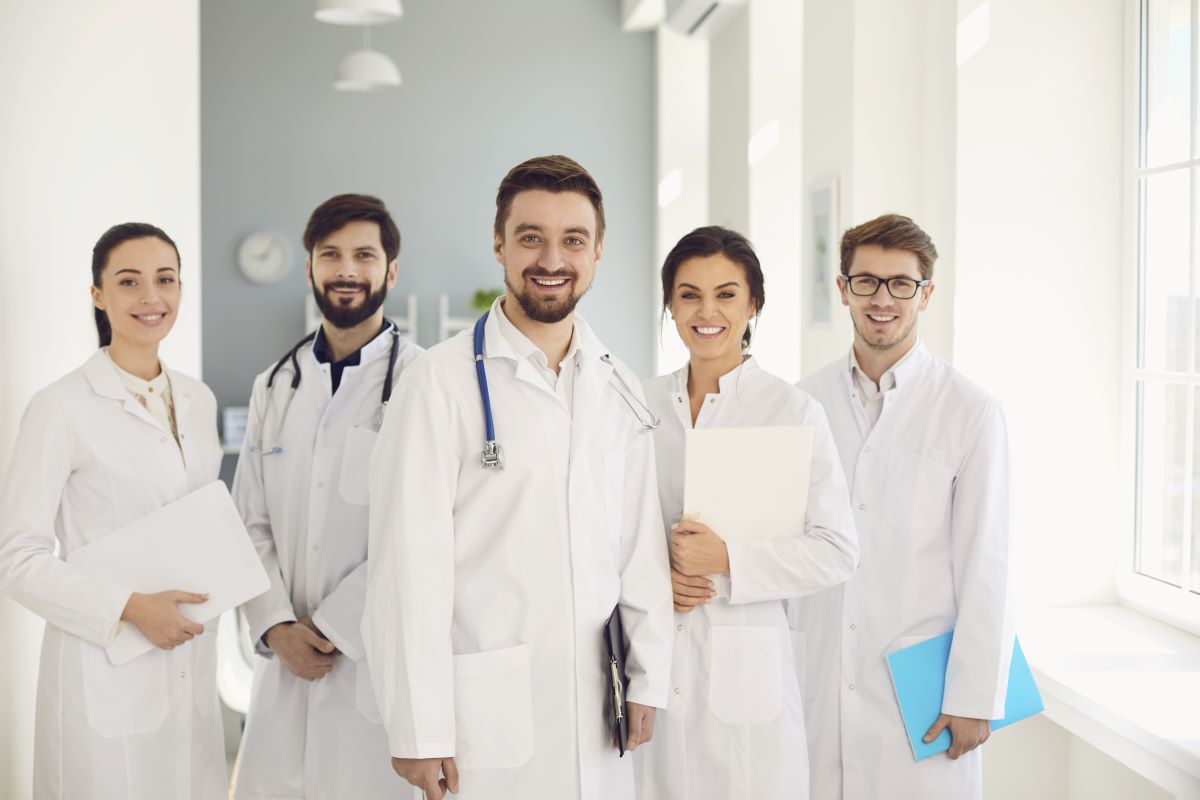 Zusehen ist eine Gruppe an Ärztinnen und Ärzten in weißen Kitteln.
