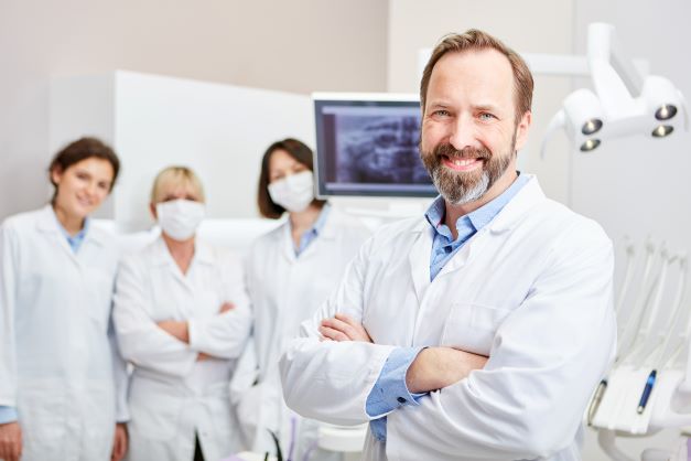 Zahnarzt steht im Vordergrund seines Praxisteams